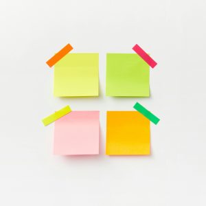 Four colorful sticky notes on white backdrop with vibrant tape. Perfect for office or organizational themes.